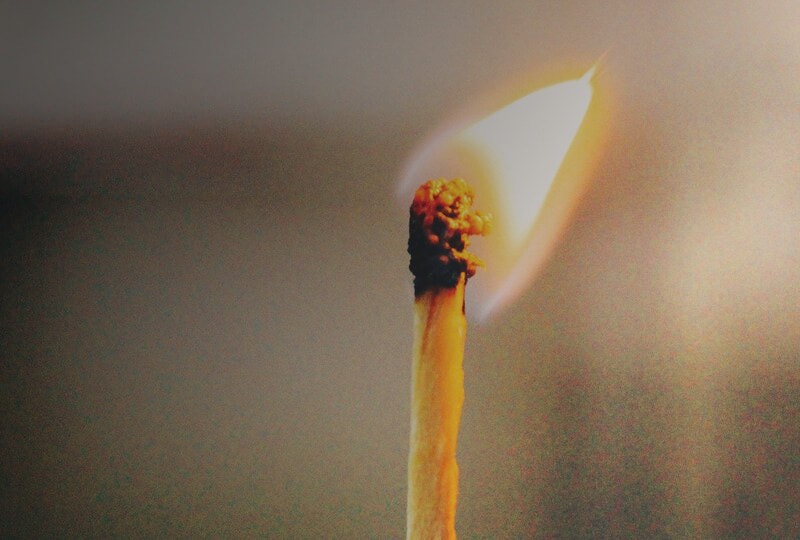 Close-up of a lit match with a glowing flame.