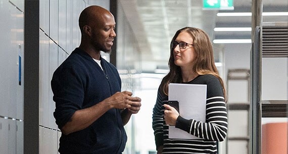 Two colleagues having a conversation in a workplace setting.