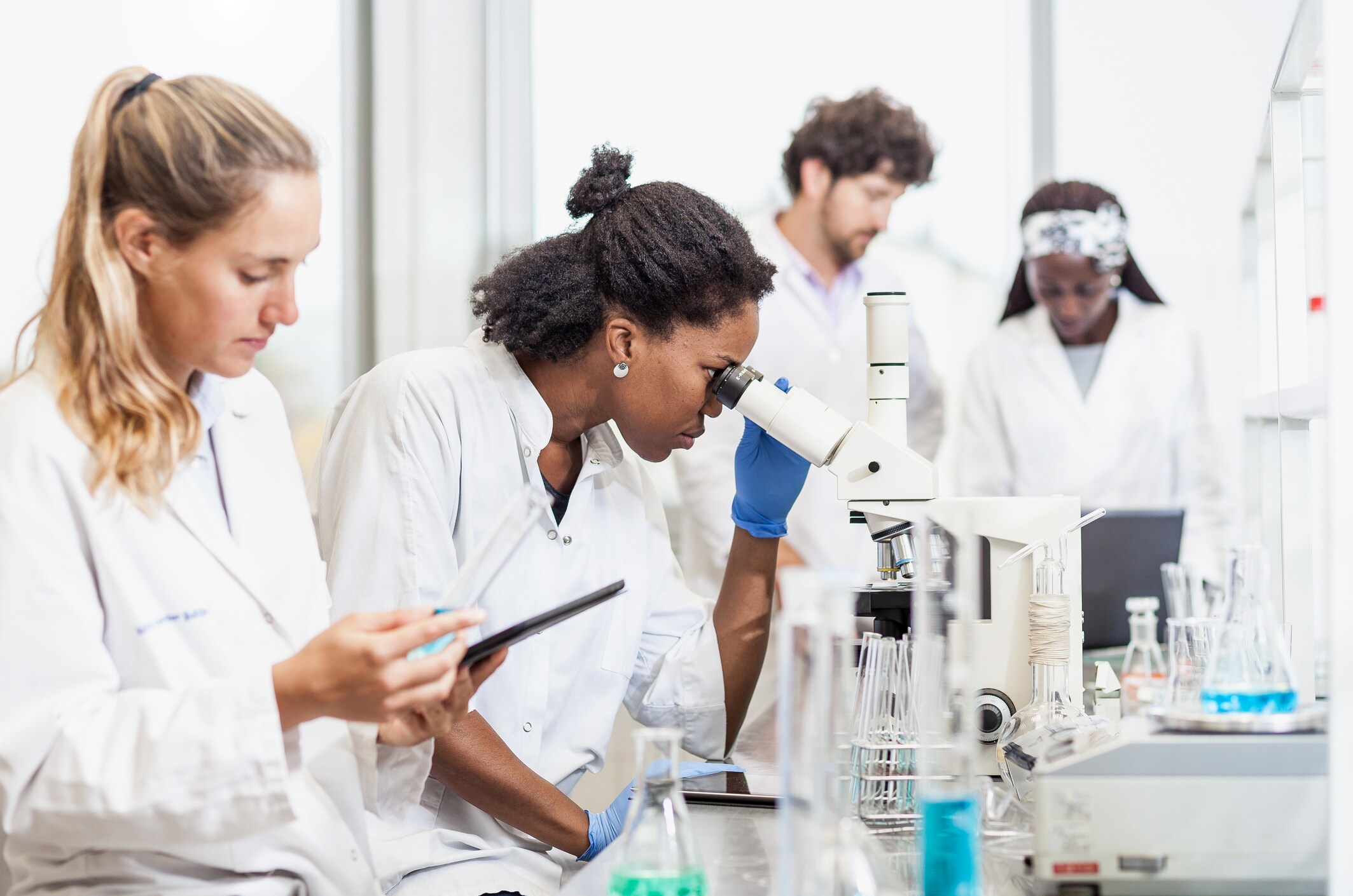 Scientists conducting laboratory research using microscopes and analytical equipment.