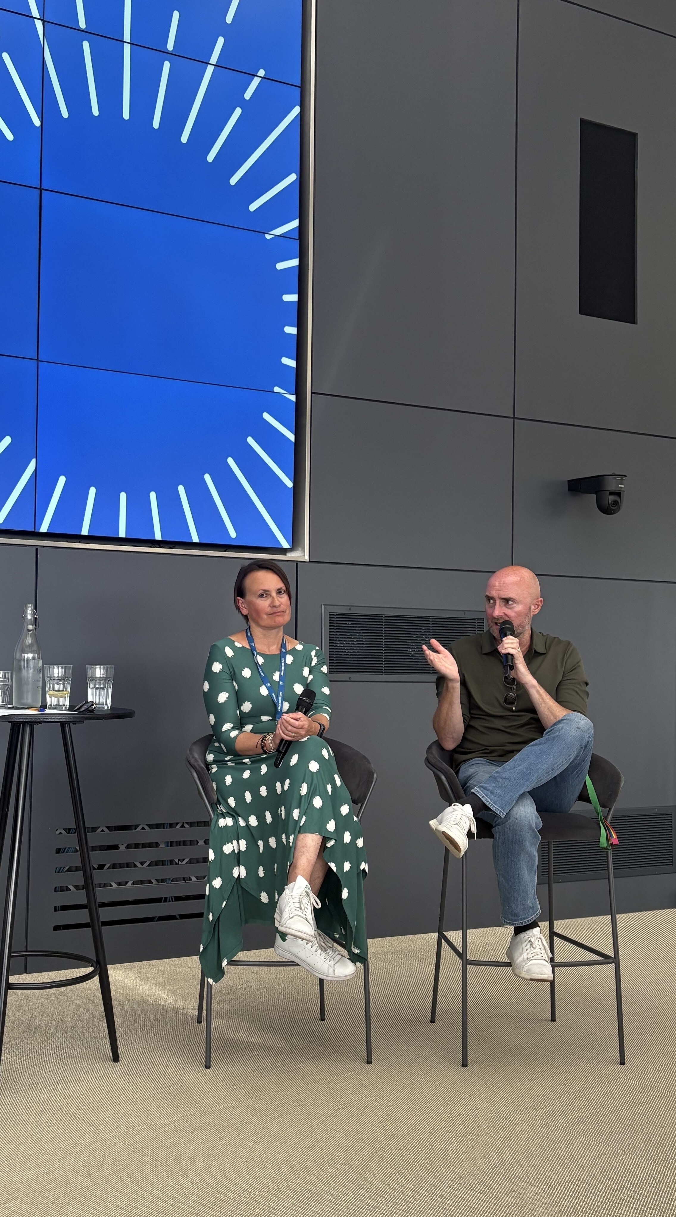 two people sit on stage during a discussion event