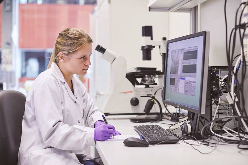 Scientist sitting at desk with computer and writing